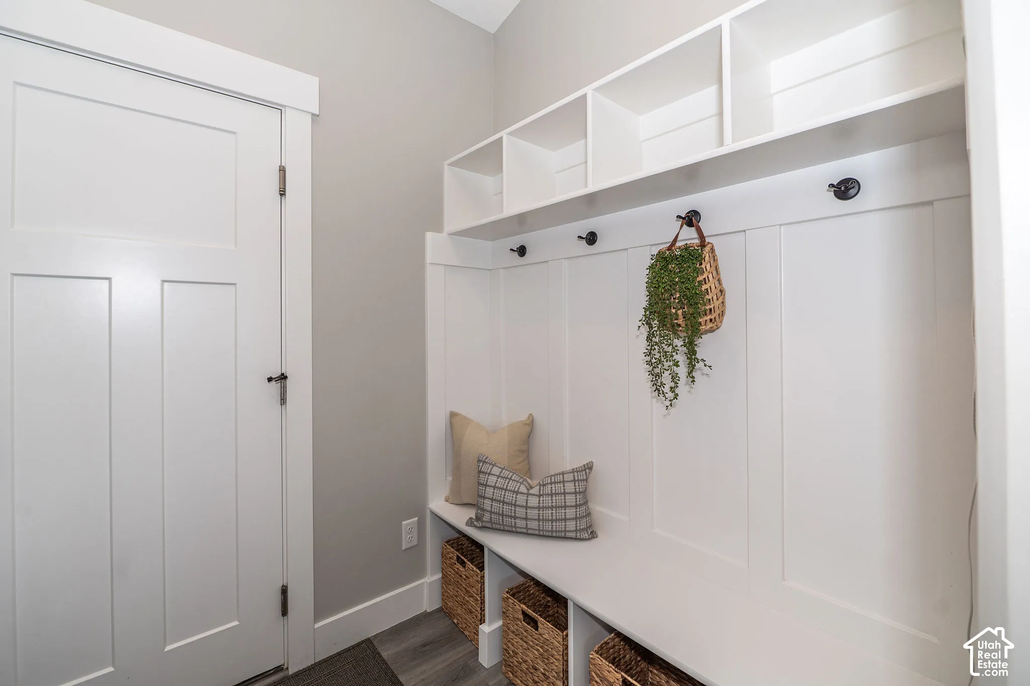 Built-in white storage bench with integrated shelving and wall hooks