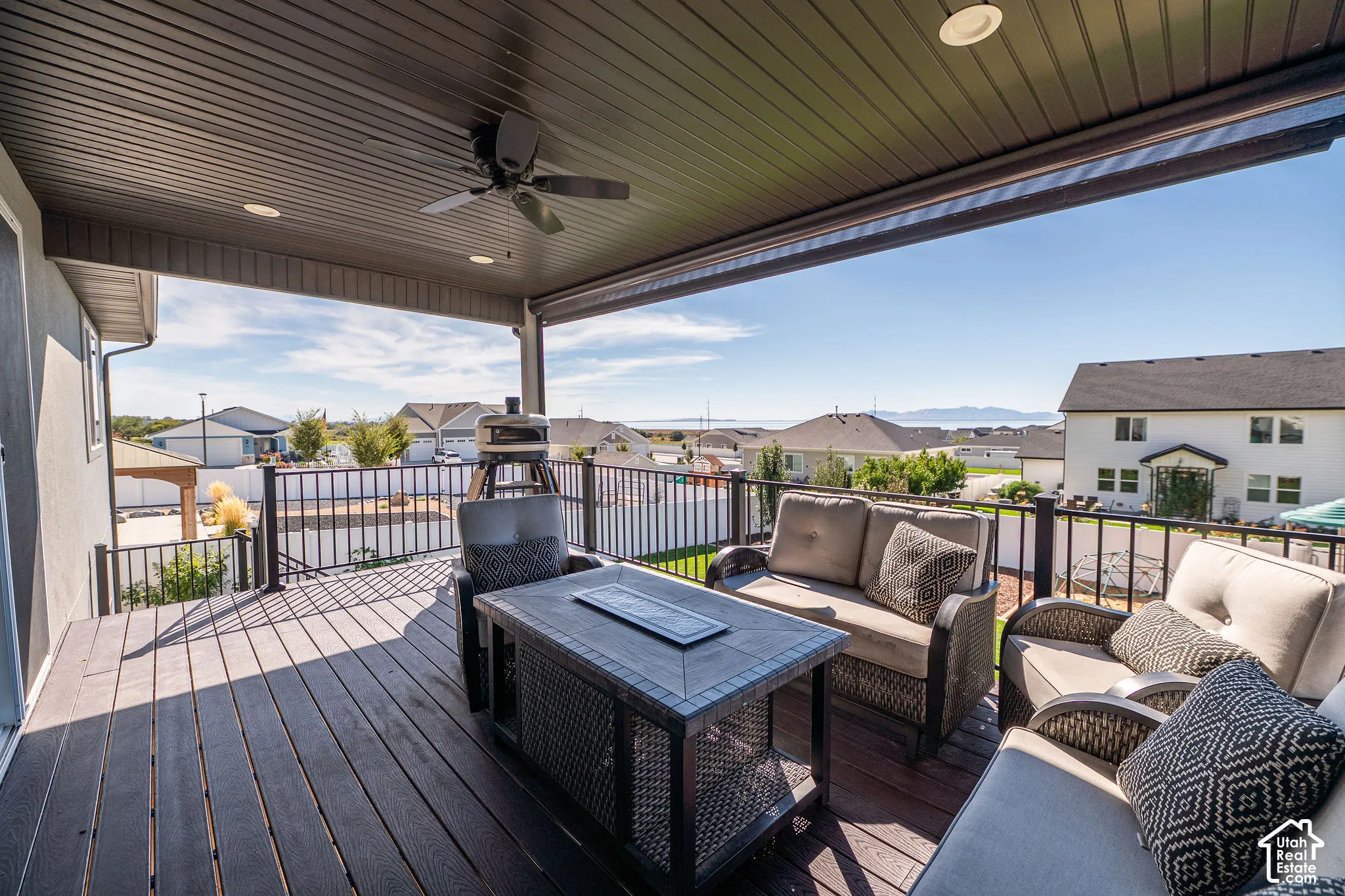 Expansive covered deck featuring composite decking, metal railings, a ceiling fan, and recessed lighting