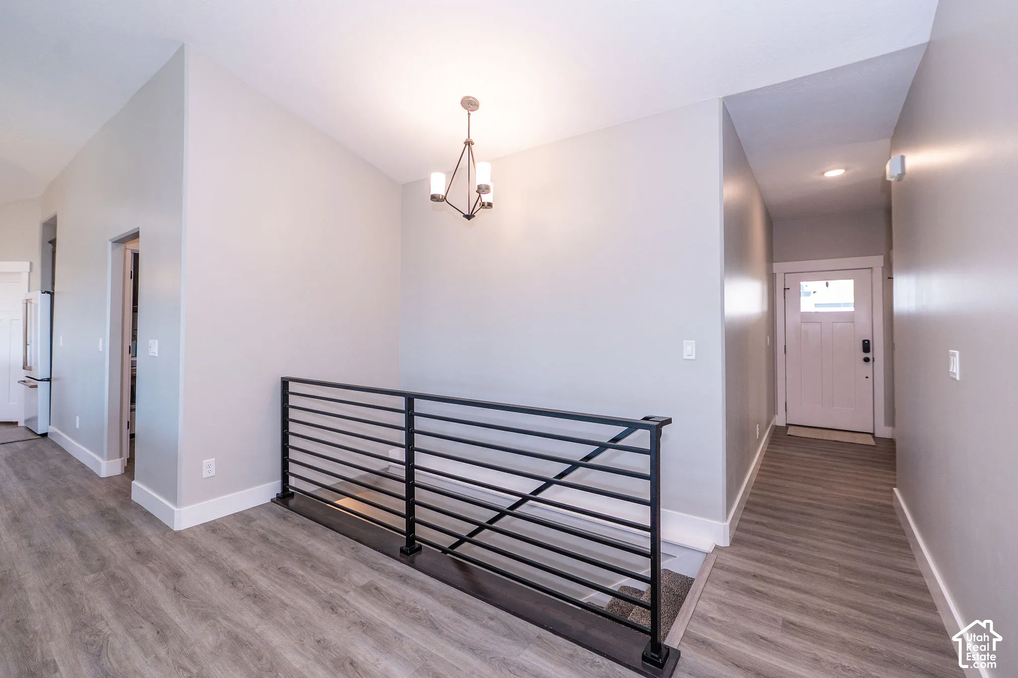 Wood-finish flooring throughout, modern metal railing, and a contemporary chandelier