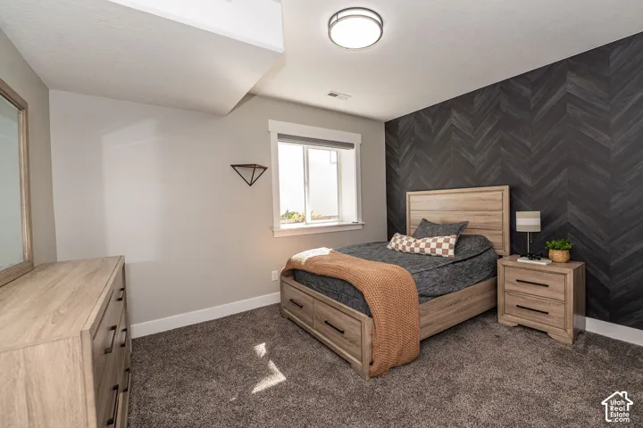 Herringbone accent wall, carpeted flooring, and a flush mount ceiling light