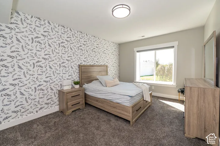 Textured accent wall, neutral wall paint, flush mount ceiling light, carpeted flooring, and a large window with a white frame
