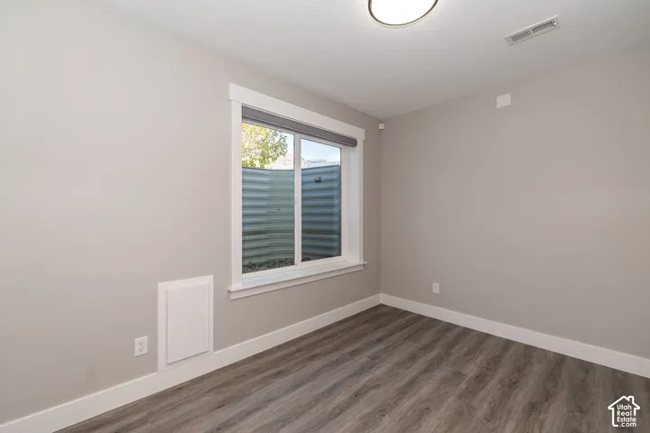 Wood-finish flooring, neutral wall tones, and a window with white trim