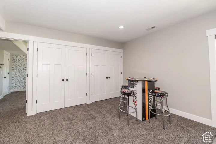 Recessed lighting, light gray wall paint, white trim, paneled doors with black hardware, and gray carpet flooring