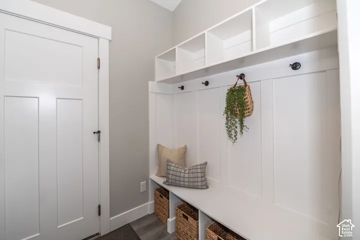 Built-in white storage bench with integrated shelving and wall hooks