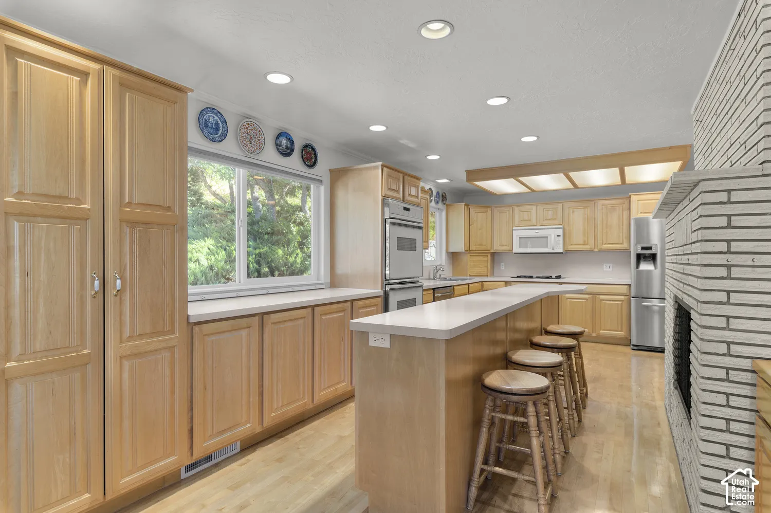Kitchen featuring extensive cabinetry, a built-in double oven, recessed lighting, and a white brick fireplace