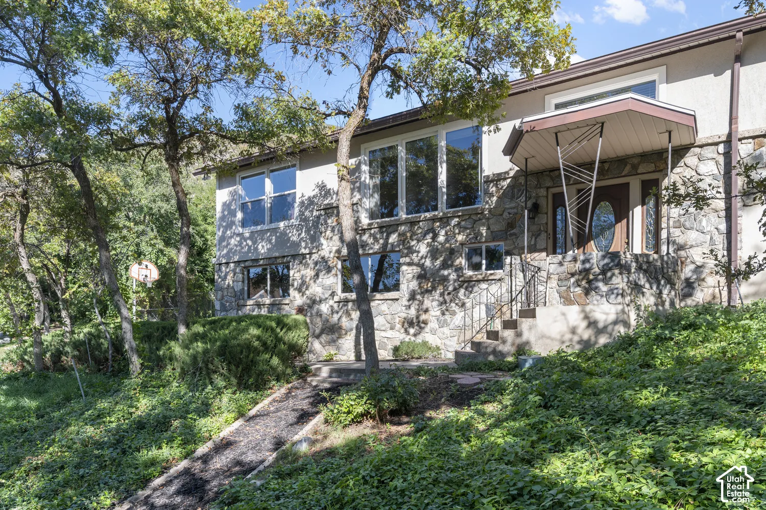 Stucco and stone exterior with mature trees