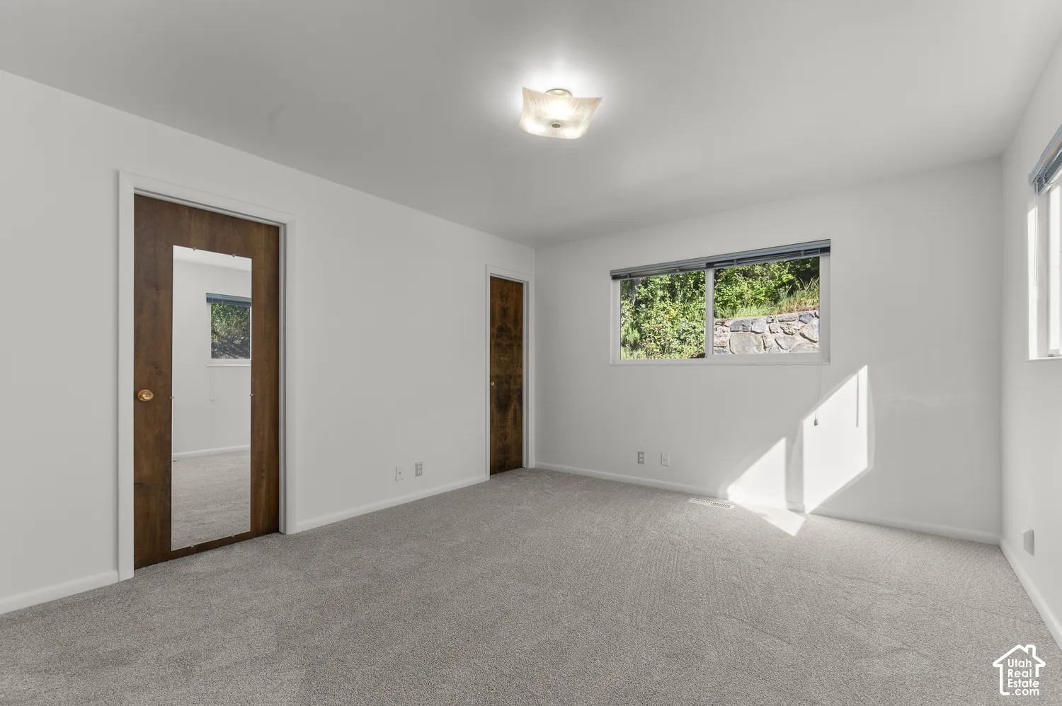 Neutral wall paint, light gray carpeting, wood-finish doors, and a ceiling-mounted light fixture