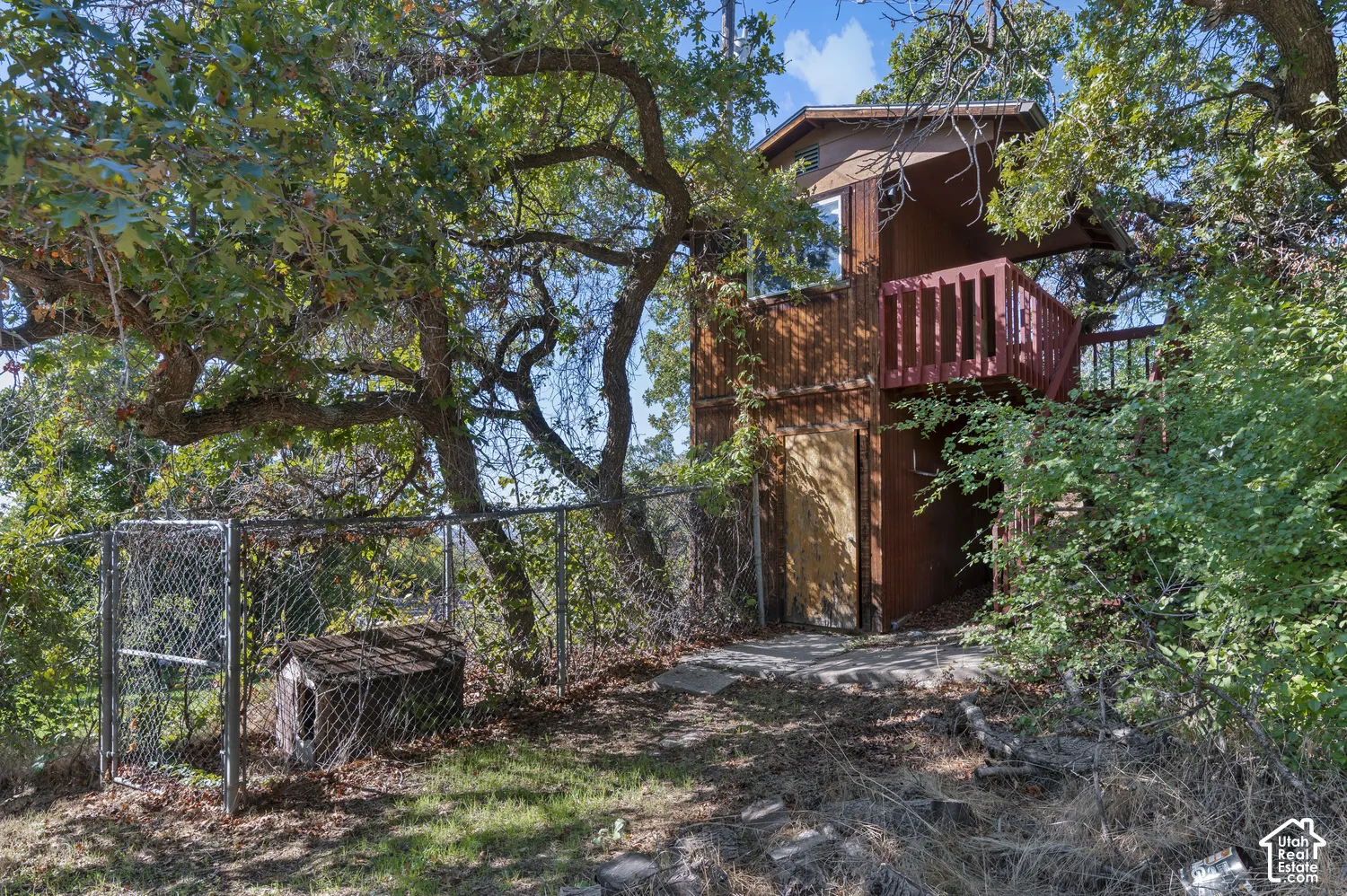 Wood-clad exterior with a built-in balcony, surrounded by mature trees