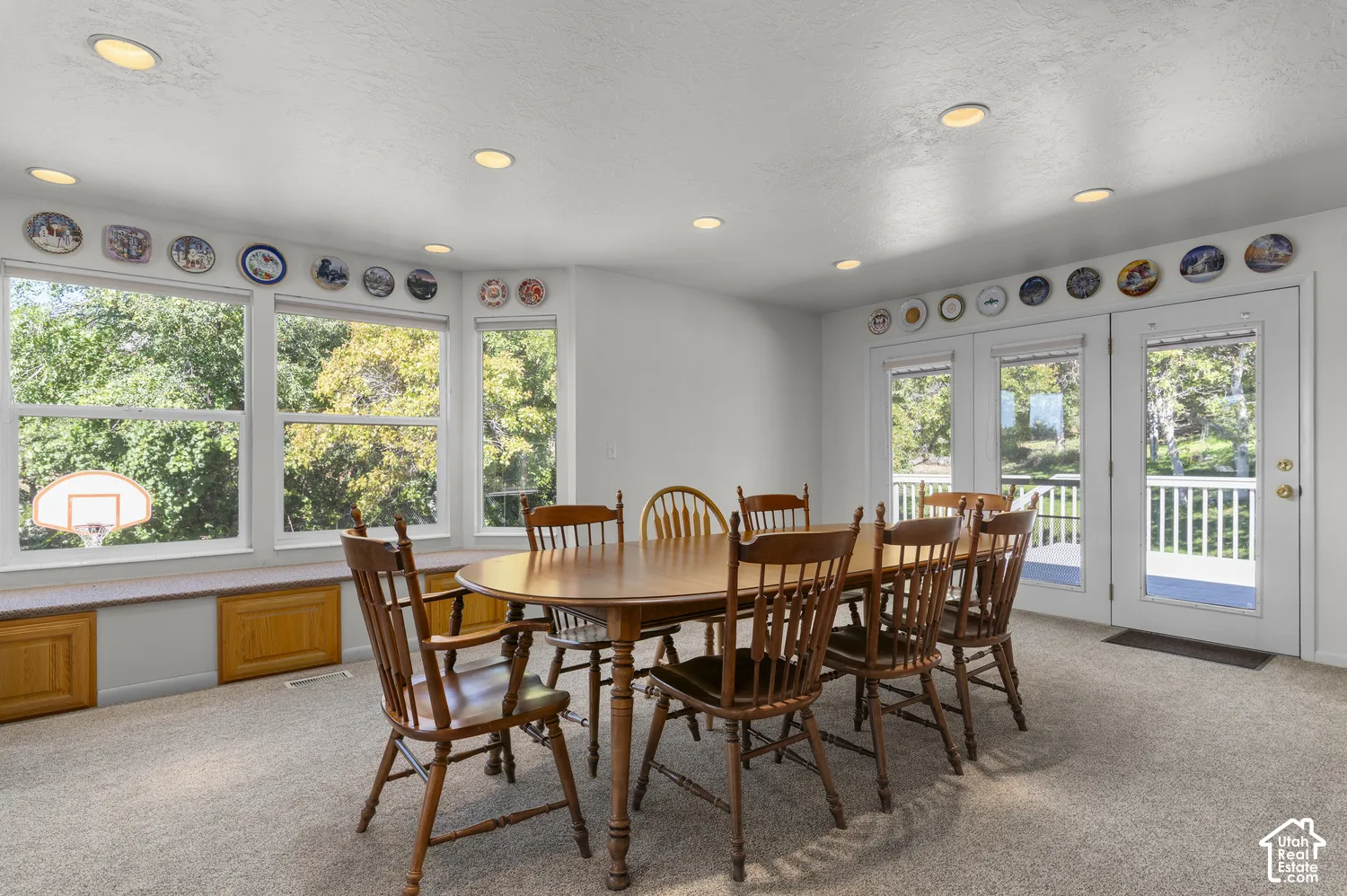 Recessed ceiling lighting, multiple large windows, window bench with built-in storage, and glass-paned double doors