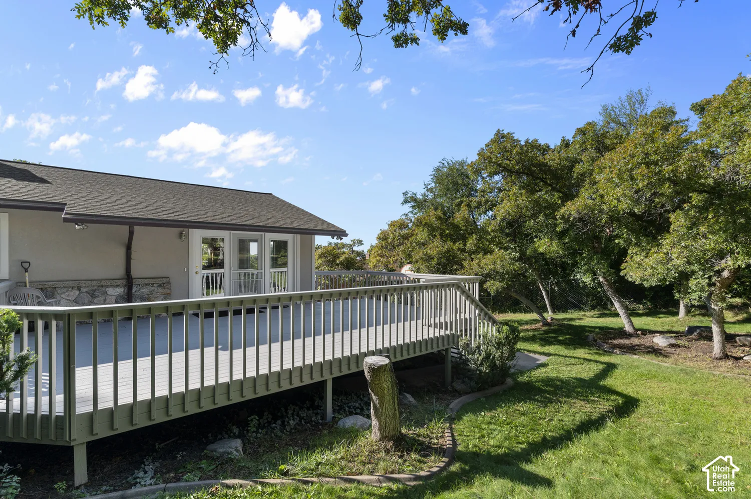 Expansive wooden deck with railing, dual glass-paned doors, and exterior stone detailing