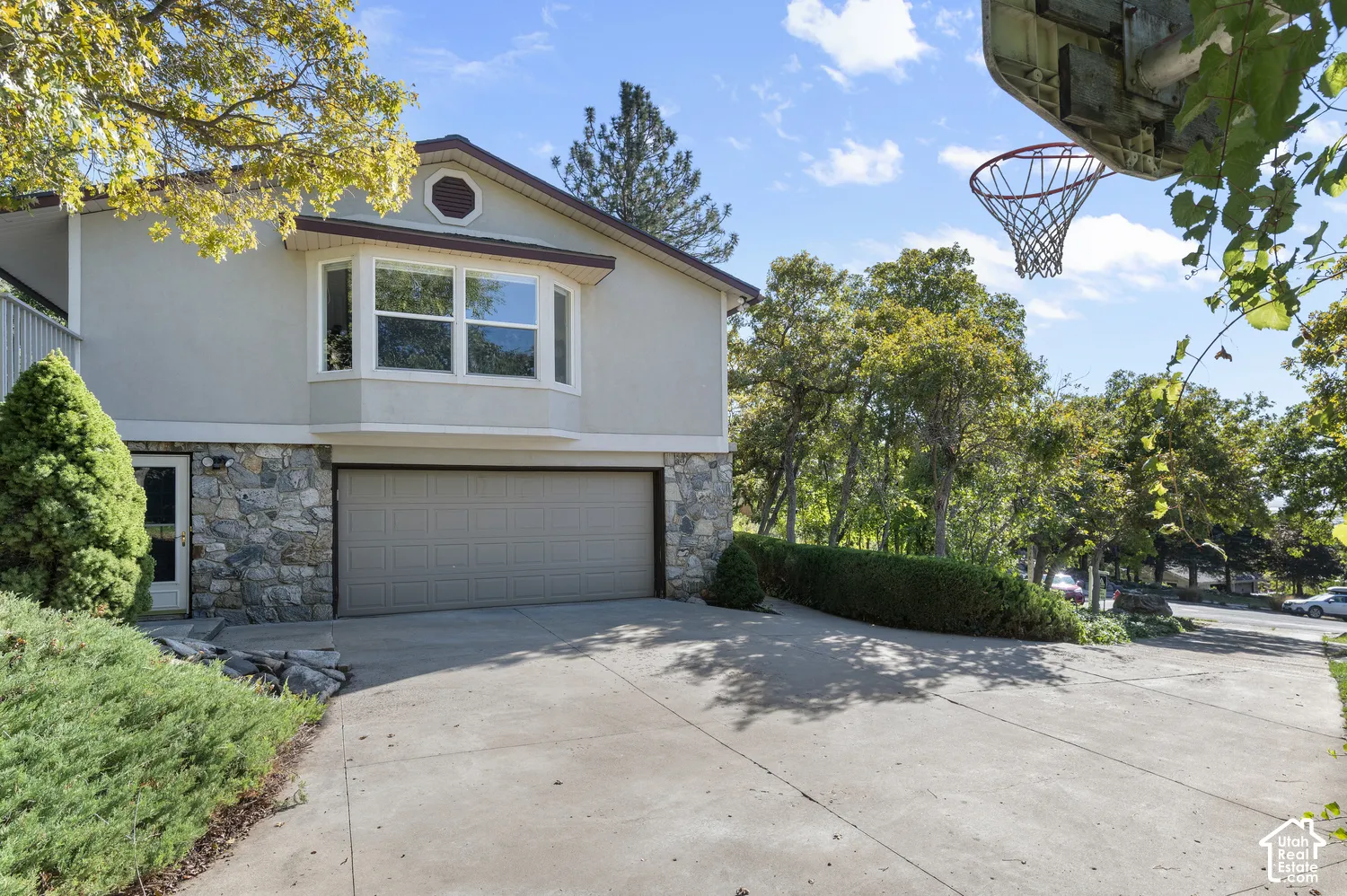 Exterior featuring a stone facade, stucco siding, an integrated garage, and a concrete driveway