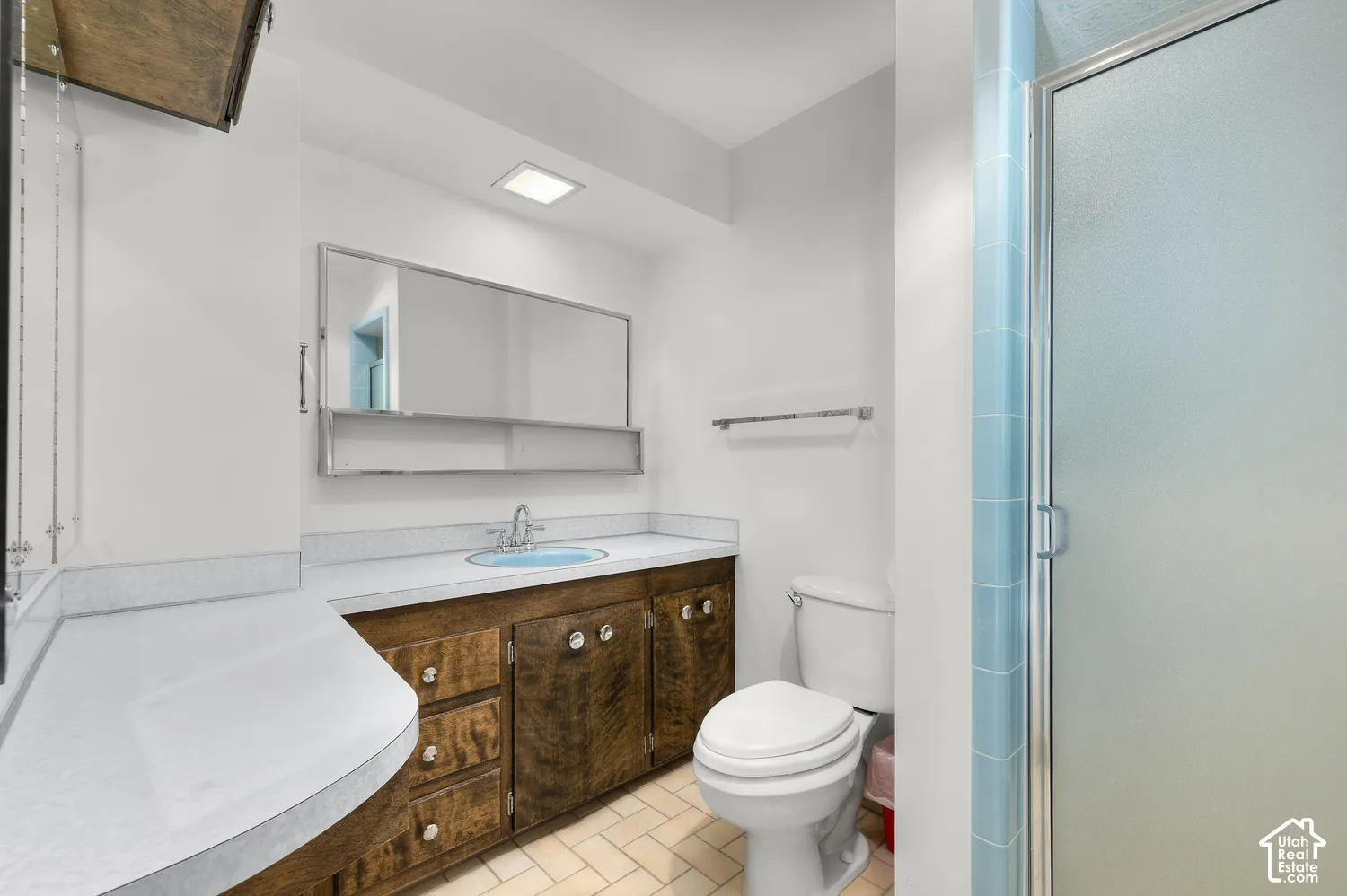 Bathroom featuring a wood-finish vanity with a laminate countertop and an integrated sink with a chrome faucet