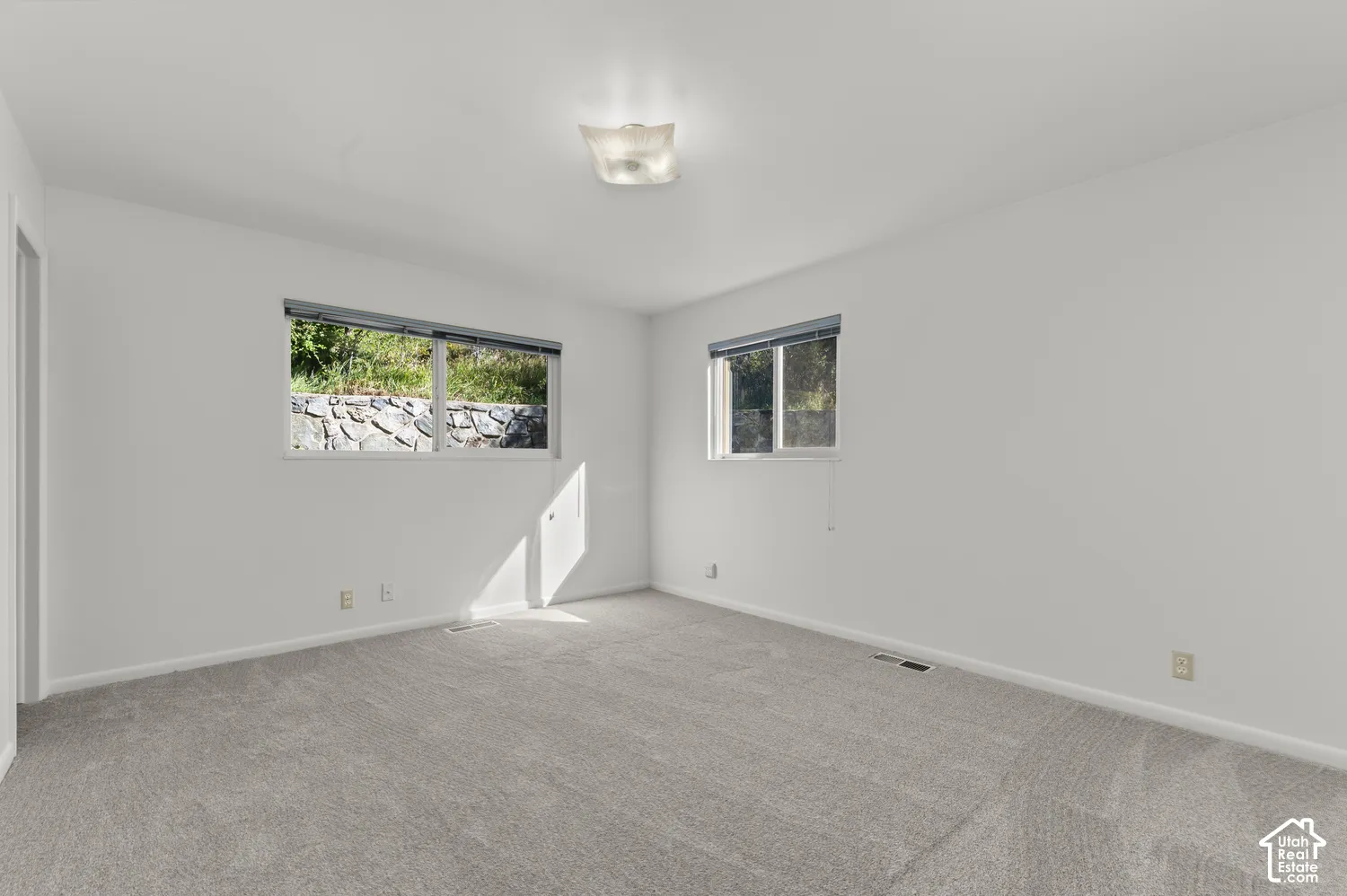 Neutral-toned carpeting, white painted walls, and a ceiling-mounted light fixture