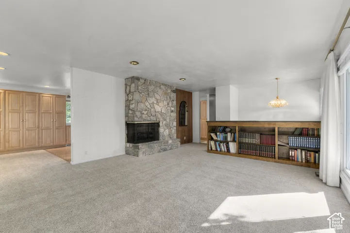 Stone fireplace with hearth, built-in shelving, recessed lighting, and wood-finish cabinetry