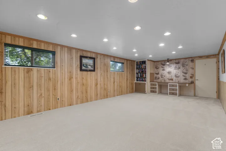 Recessed lighting illuminates the carpeted flooring and wood paneling