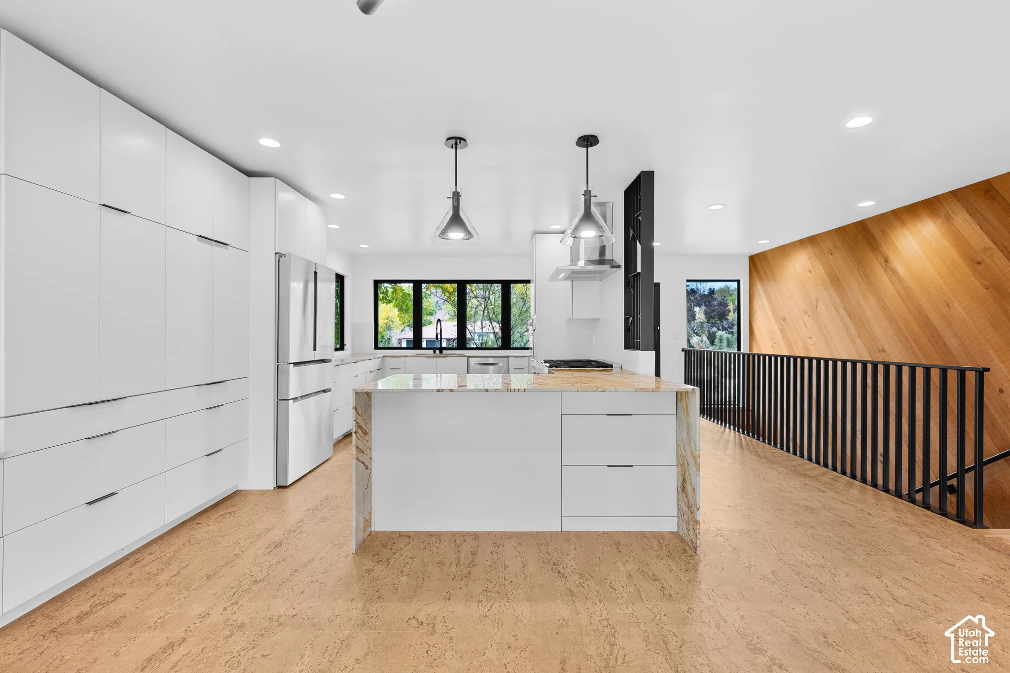 Modern kitchen featuring a central island with a light-toned countertop, a full suite of stainless steel appliances, and extensive white cabinetry