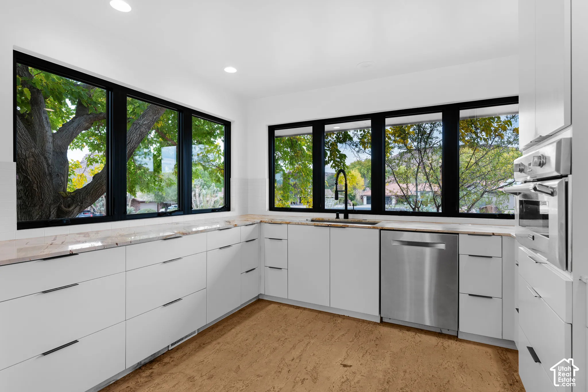 Contemporary kitchen featuring extensive white cabinetry, light-toned countertops, and recessed lighting