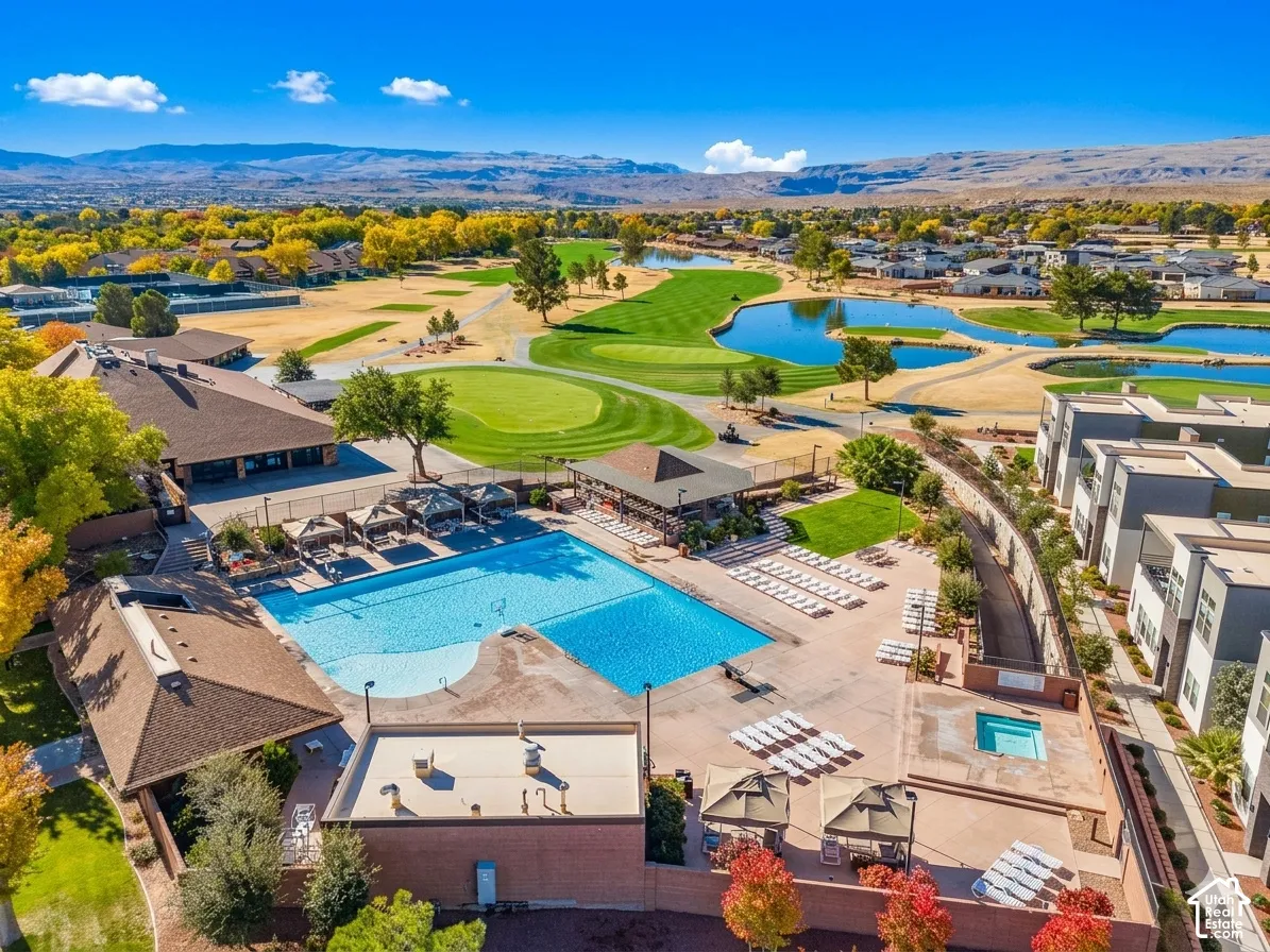 Expansive outdoor swimming pool with surrounding lounge areas, additional smaller pool, and buildings featuring a brown shingle roof
