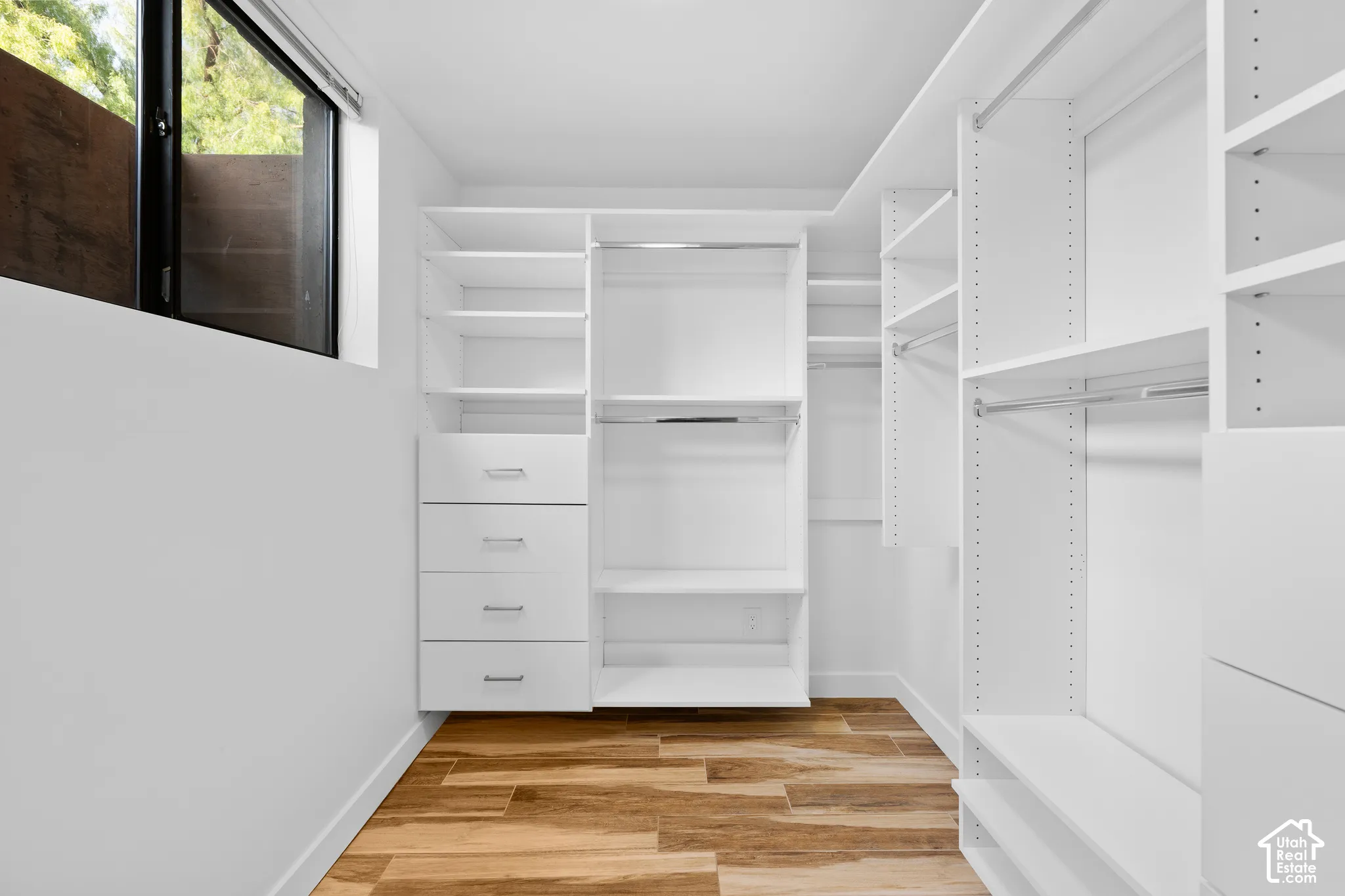 Built-in closet system featuring white shelving, multiple hanging rods, and integrated drawers