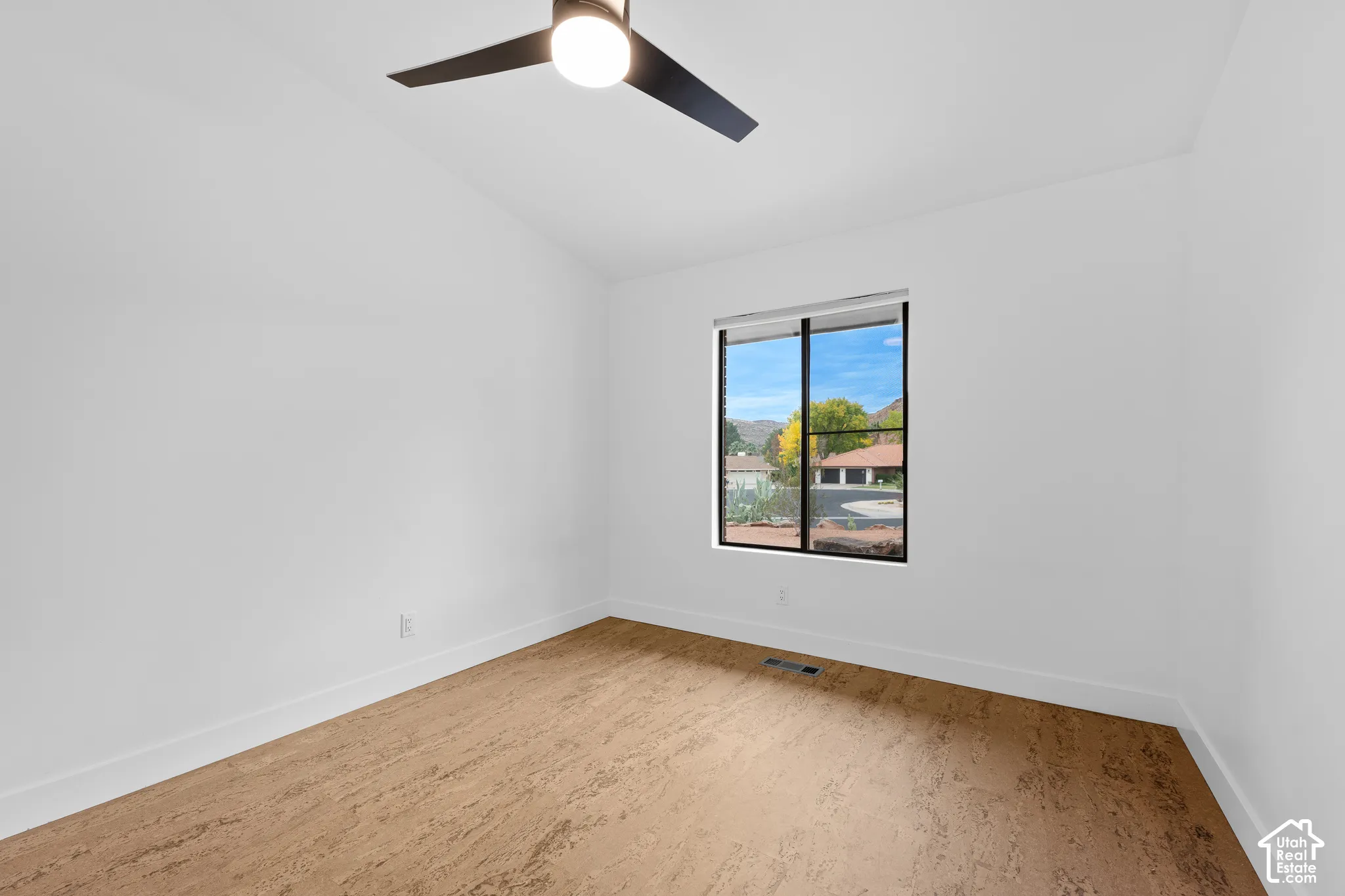 Vaulted ceiling with a contemporary ceiling fan, wood-finish flooring, and a large window with black framing