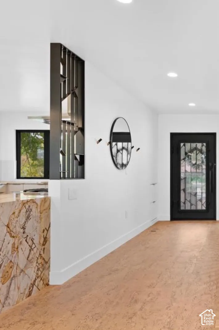 Recessed lighting illuminates the entryway, featuring cork flooring and a decorative room divider