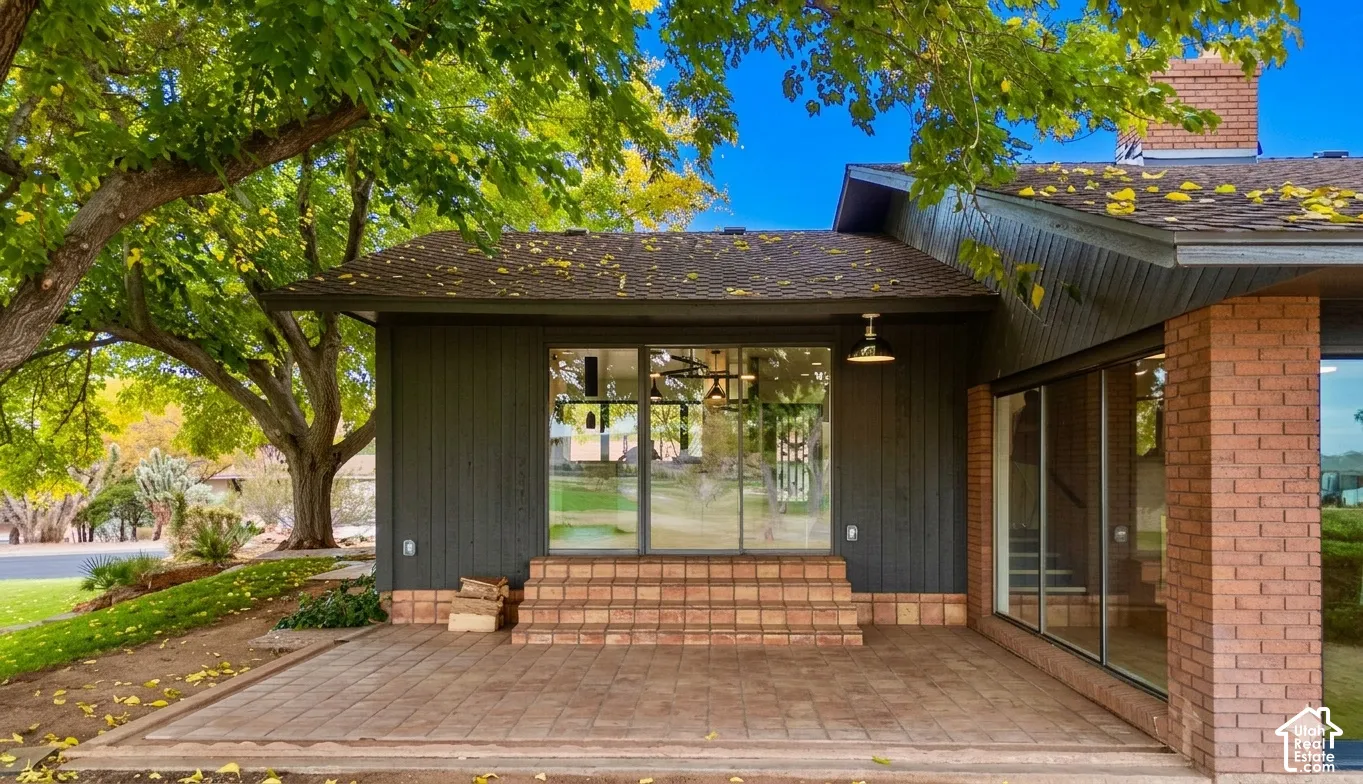 Paver patio with brick steps, large glass sliding doors, and a brick exterior accent