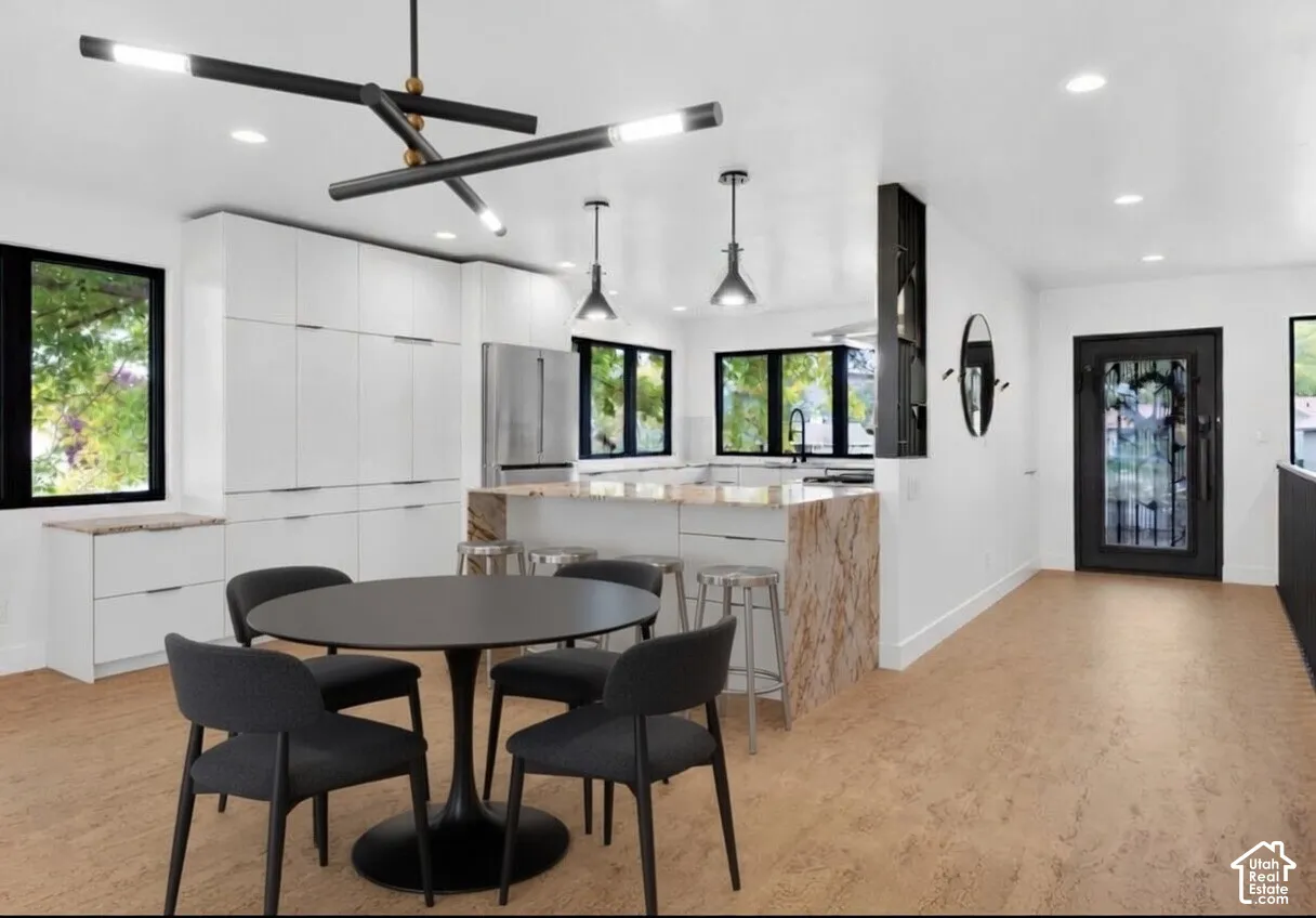 Modern kitchen featuring sleek white cabinetry, stainless steel appliances, and a central island with natural stone-finish countertops