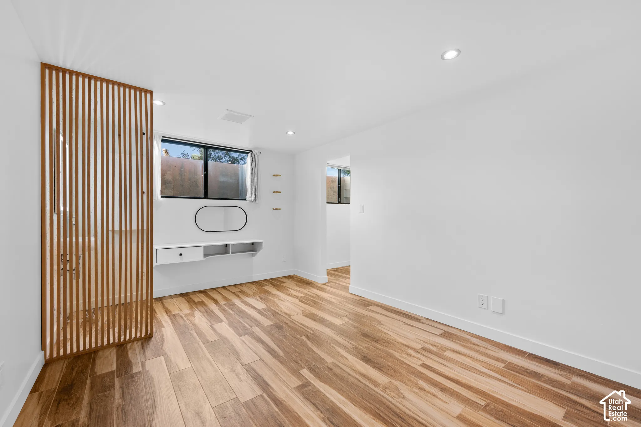 Wood-finish flooring throughout, recessed lighting, and a modern built-in desk with shelving