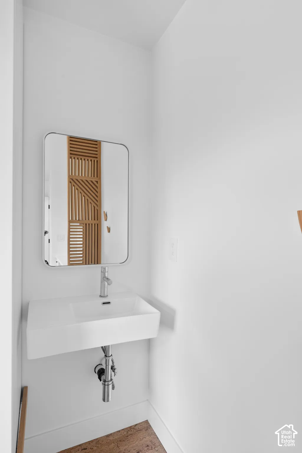 Wall-mounted rectangular sink with a chrome faucet, paired with a rounded rectangular mirror