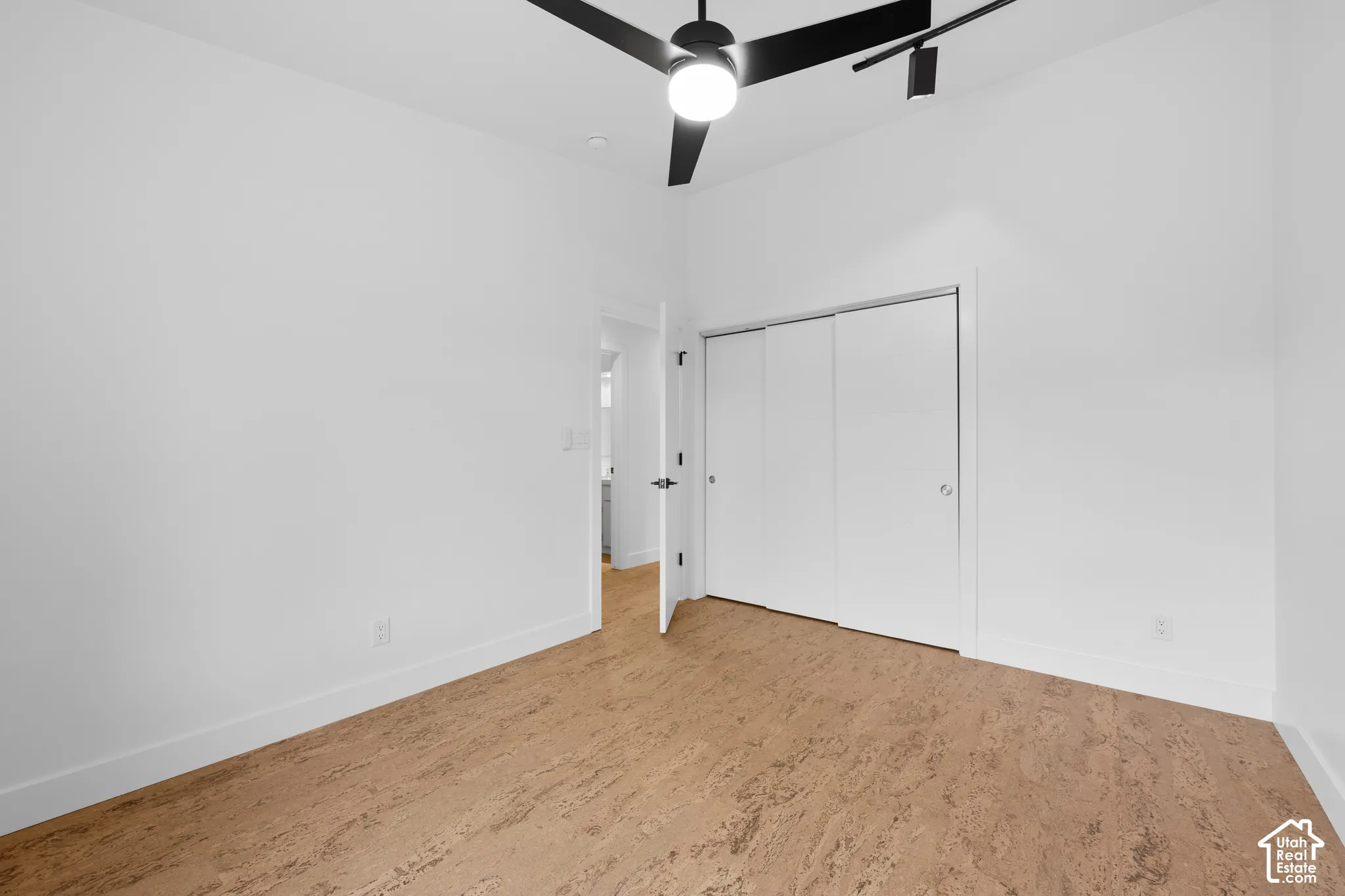 Bright room featuring cork flooring, a ceiling fan with integrated lighting, and a closet with sliding doors