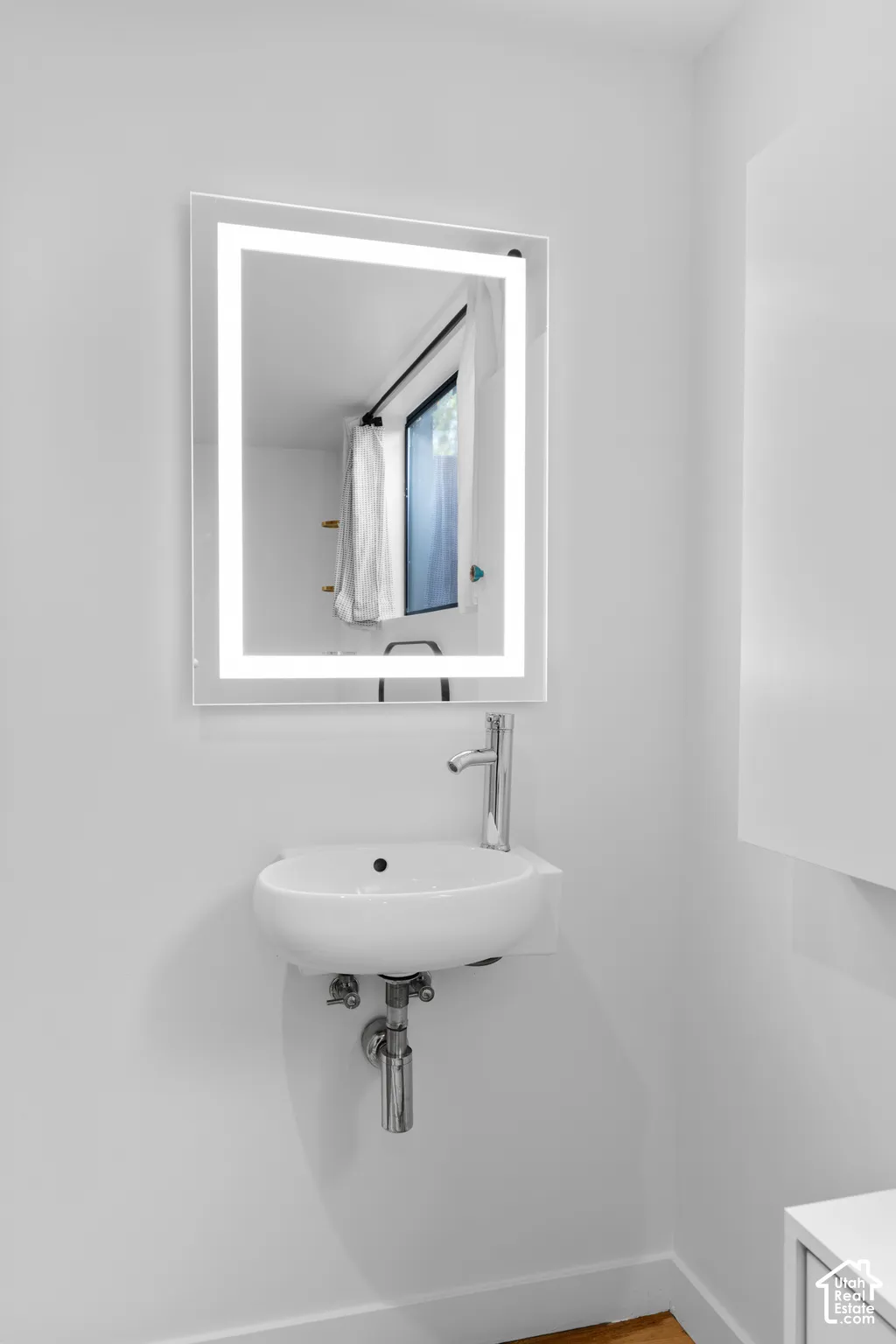 Wall-mounted vanity with a white vessel sink, polished chrome faucet, and an illuminated mirror