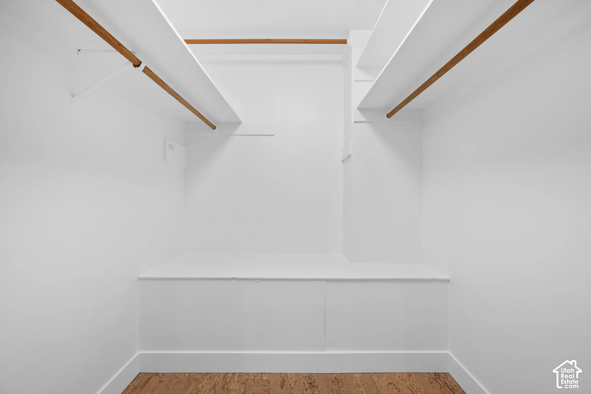 Built-in closet system featuring multiple wood-finish hanging rods, overhead shelving, and a lower built-in storage bench
