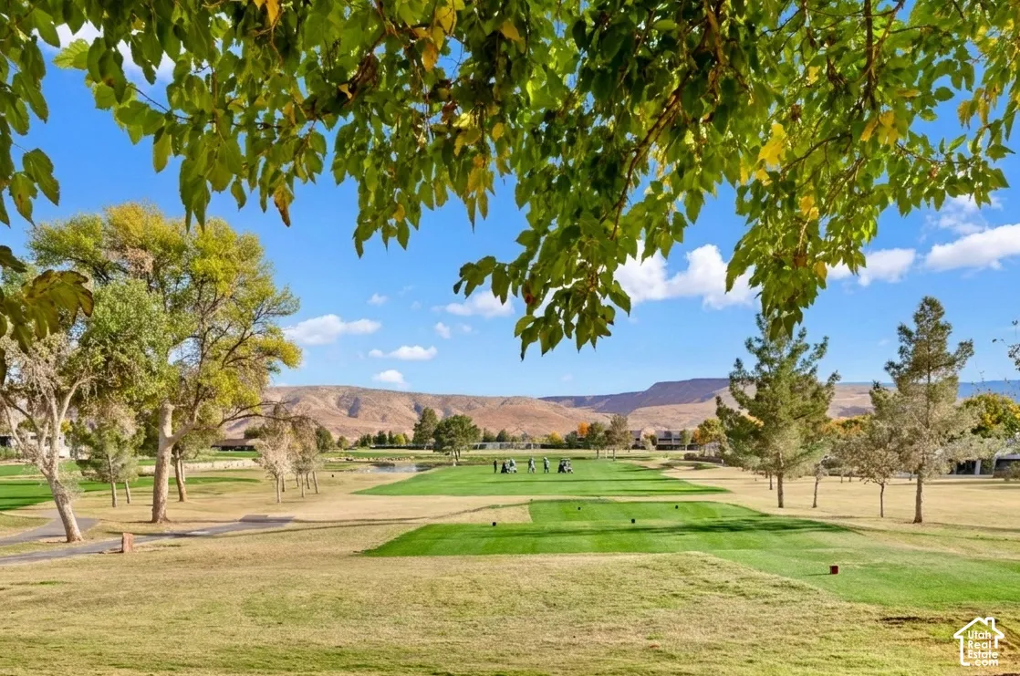Expansive golf course with manicured greens, mature trees, and mountainous terrain in the background