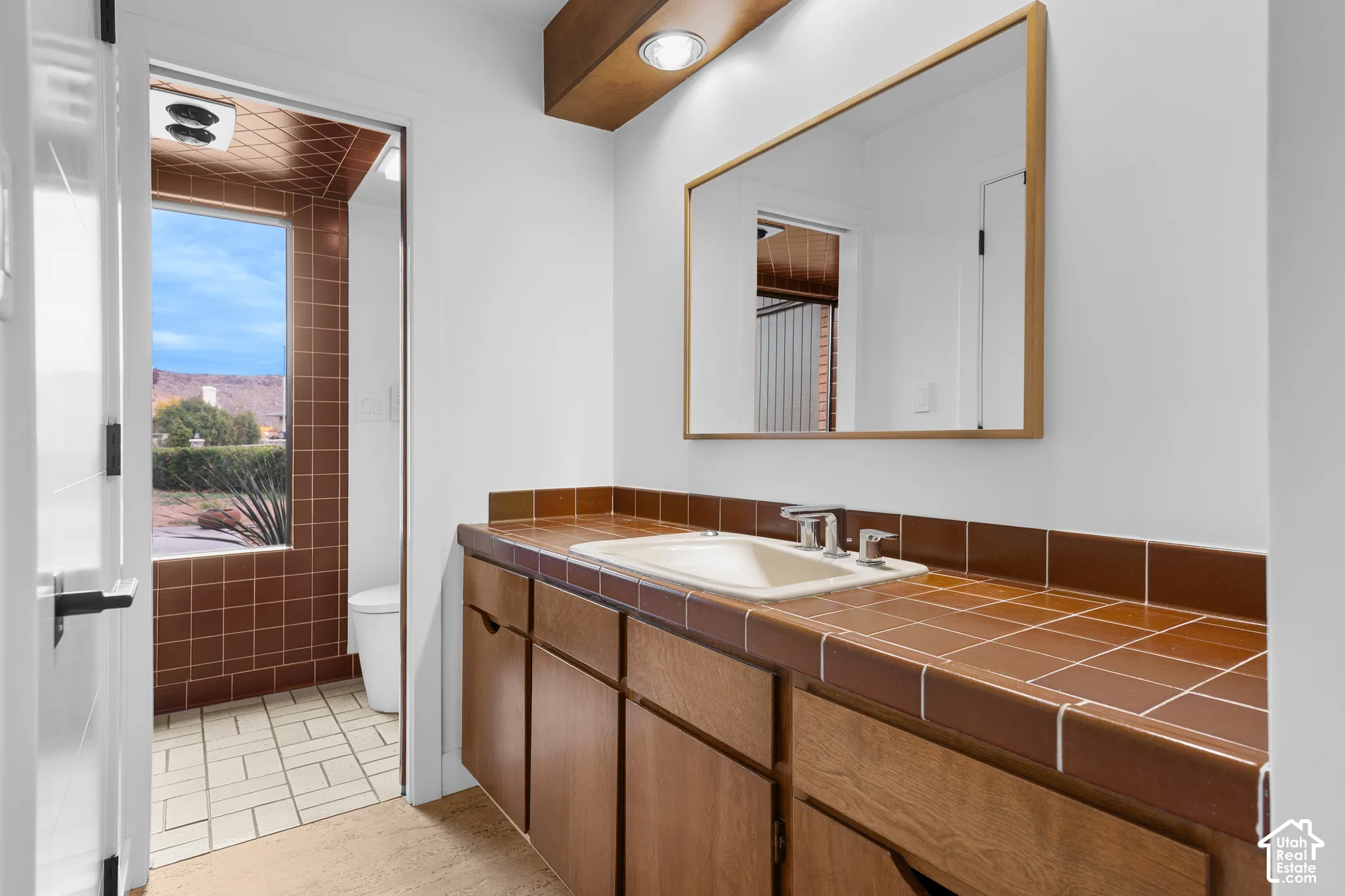 Wood-finish vanity with an integrated sink and chrome faucet