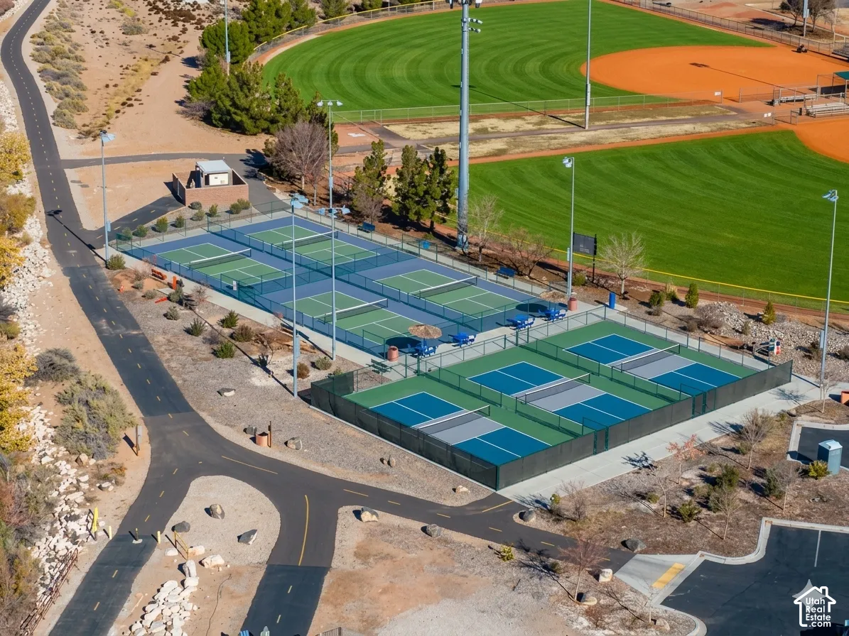 Pickleball courts with perimeter fencing, adjacent walking paths, and nearby sports fields