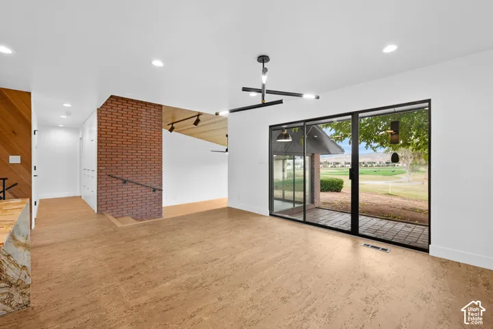 Wood-finish flooring, exposed brick wall, contemporary lighting fixture, full-height sliding glass doors, and a patio with a tiled surface