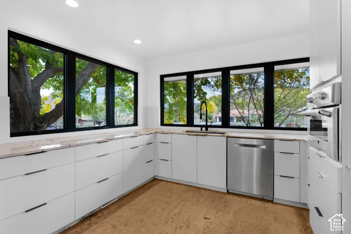 Contemporary kitchen featuring extensive white cabinetry, light-toned countertops, and recessed lighting