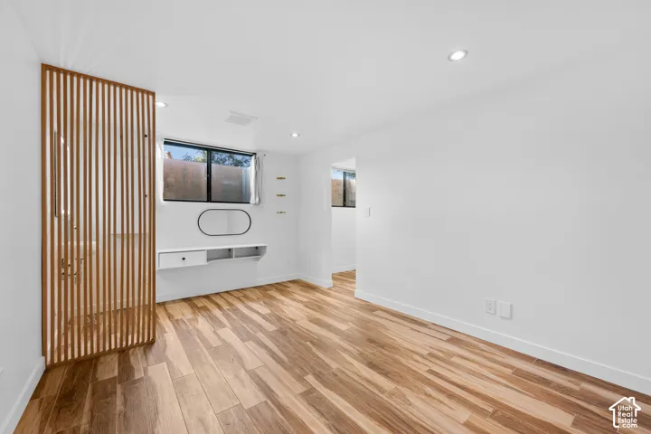 Wood-finish flooring throughout, recessed lighting, and a modern built-in desk with shelving