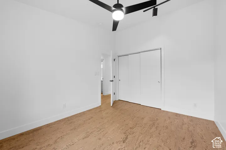 Bright room featuring cork flooring, a ceiling fan with integrated lighting, and a closet with sliding doors