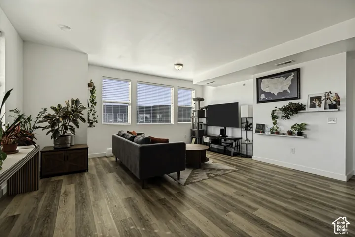 Wood-finish flooring throughout, with multiple windows featuring blinds, and recessed lighting