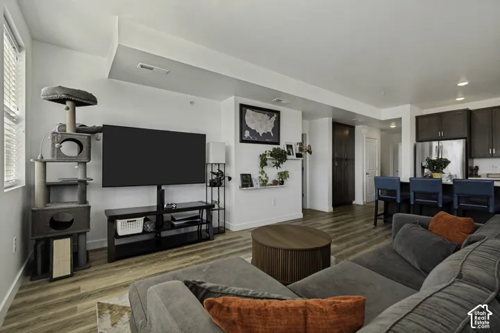 Open-concept living space featuring wood-finish flooring, recessed lighting, and a kitchen island with seating