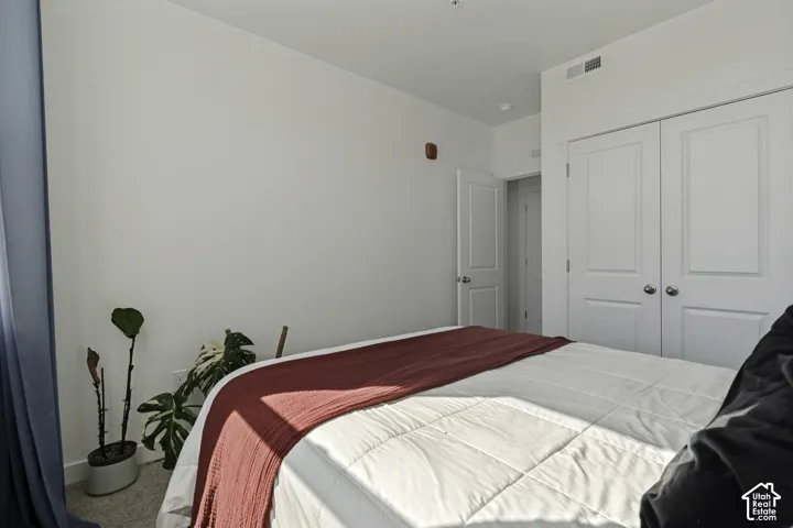 White walls with a textured finish, light gray carpet flooring, and white interior doors with round silver hardware