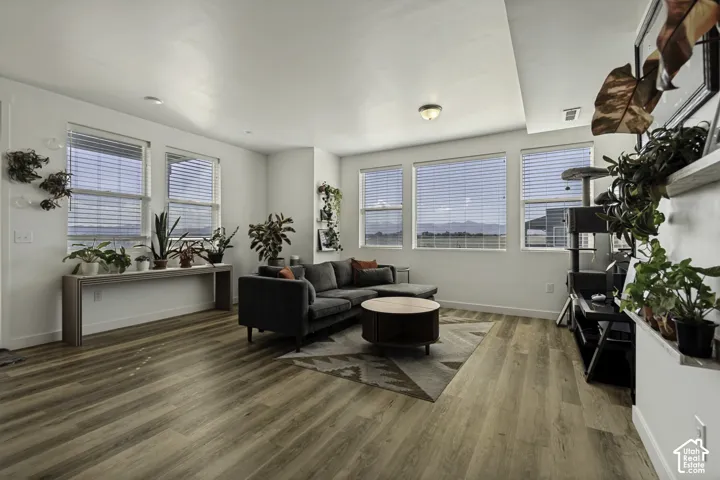 Expansive living space featuring wood-finish flooring, recessed lighting, and multiple windows with horizontal blinds