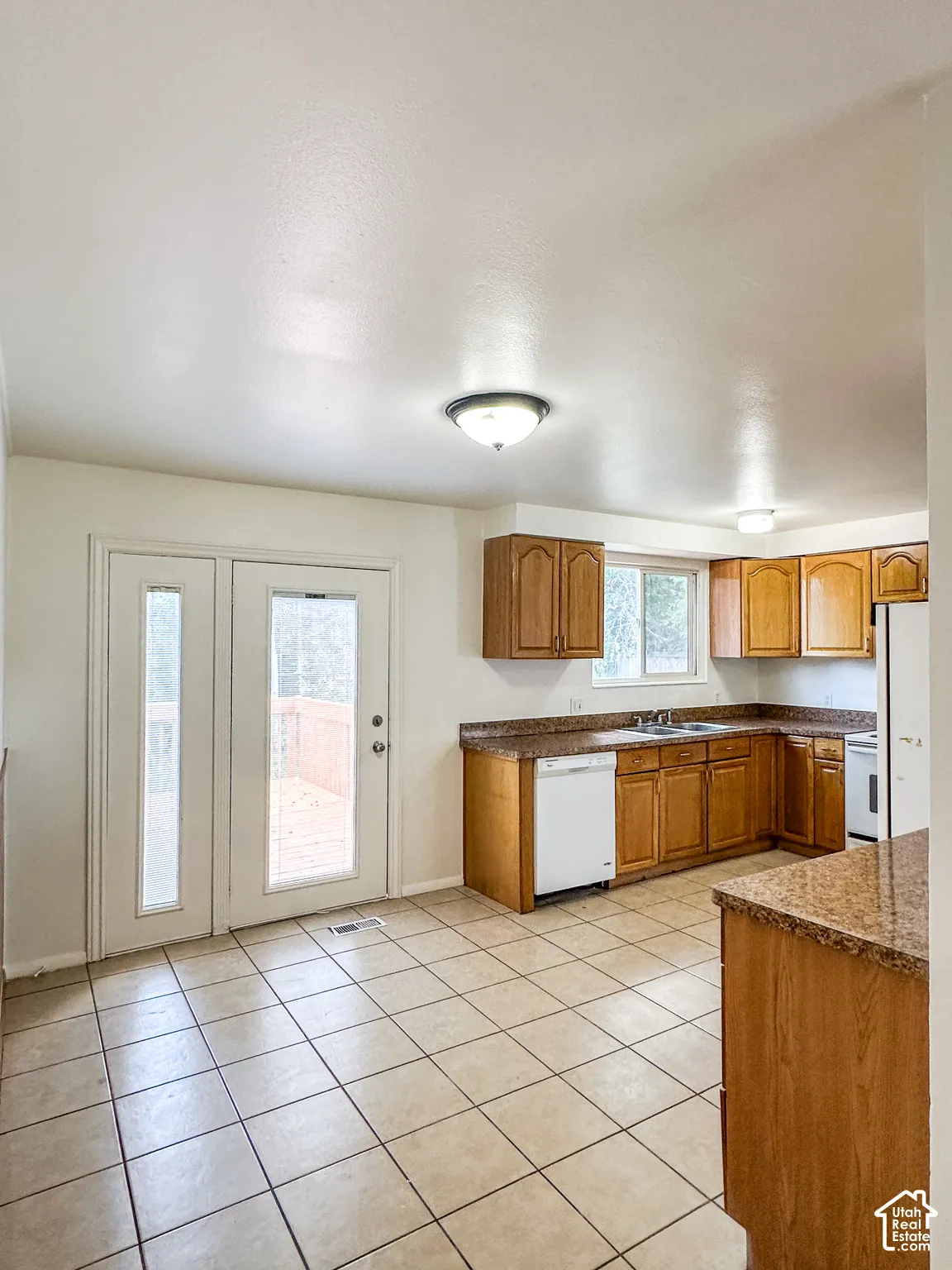 Kitchen featuring wood cabinetry, granite-finish countertops, and tile flooring