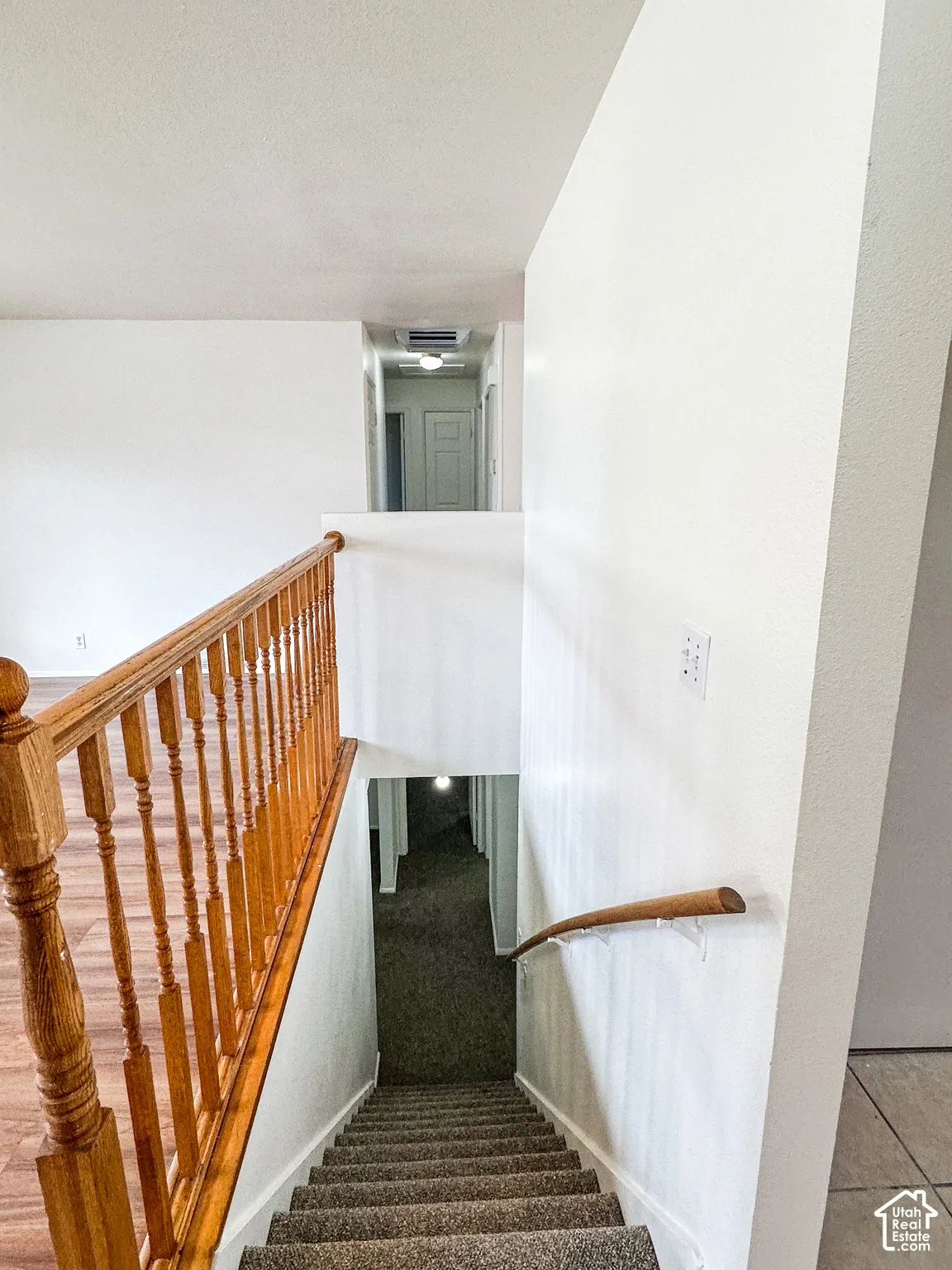 Carpeted staircase with a wood handrail and balustrade