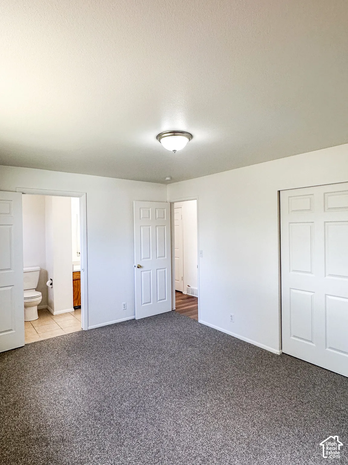Neutral-toned wall-to-wall carpeting, white walls, and a semi-flush mount ceiling light fixture