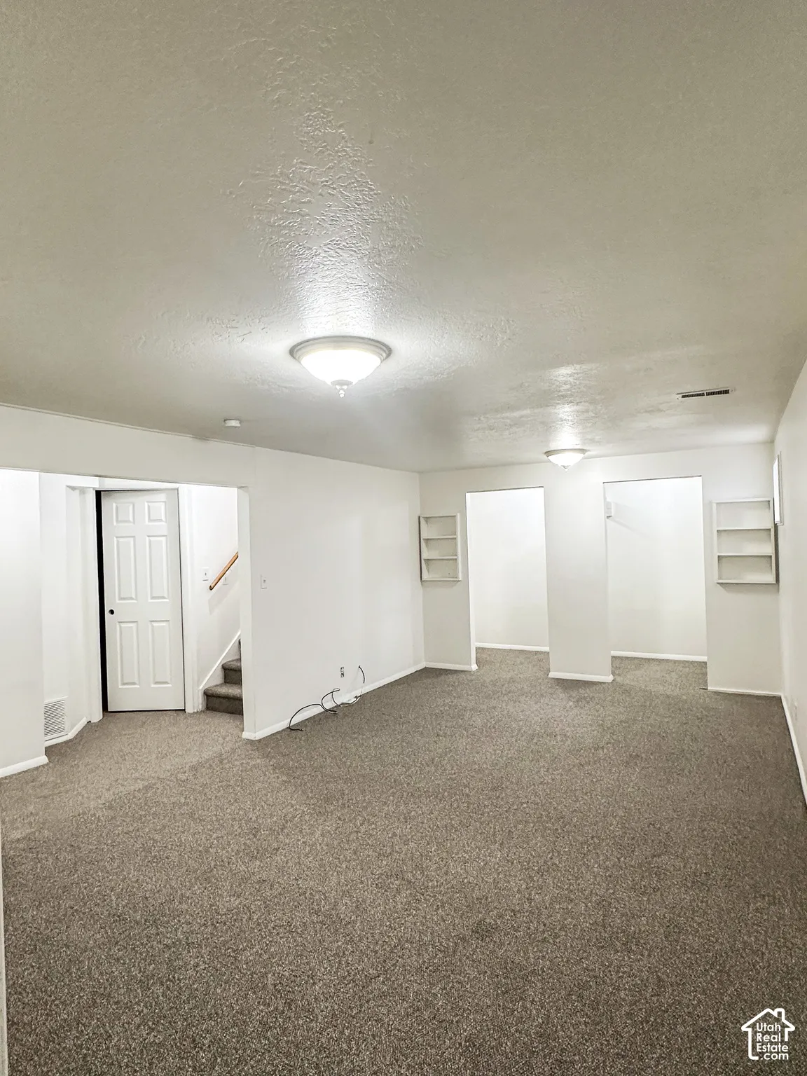 Recessed ceilings with multiple flush-mount light fixtures, neutral-toned carpeting, built-in shelving, and white interior doors