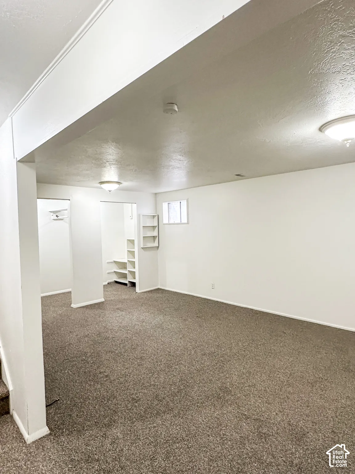 Expansive carpeted area with recessed lighting, built-in shelving, and multiple windows