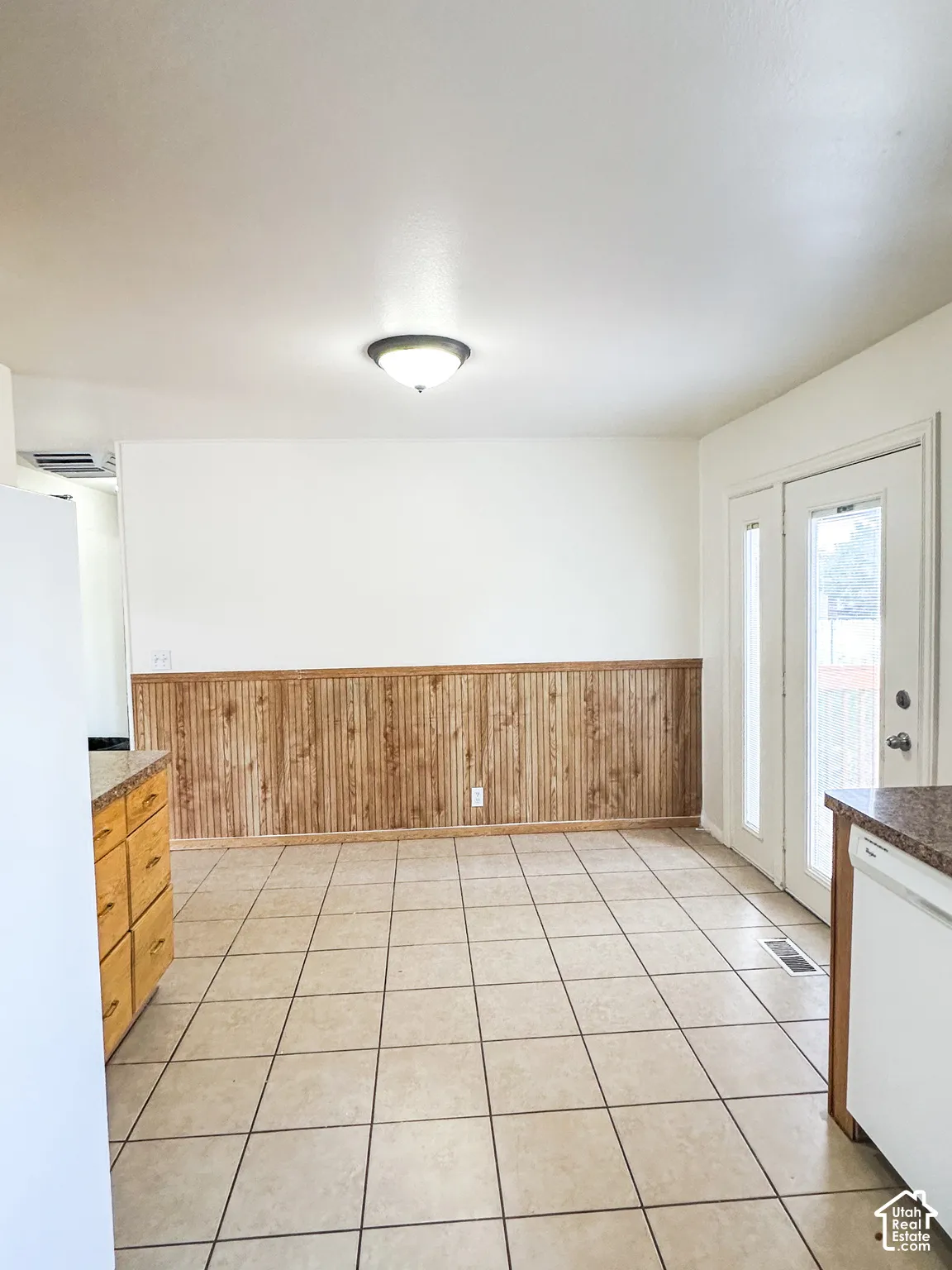 Tiled flooring with contrasting grout, wood paneling, white walls, and a ceiling-mounted light fixture