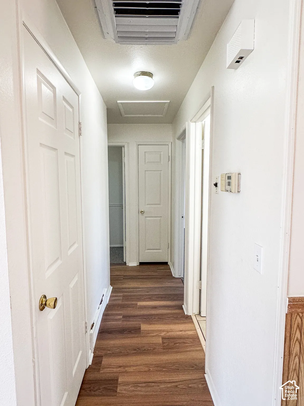 Hallway featuring wood-finish flooring, white paneled doors, and a ceiling-mounted light fixture